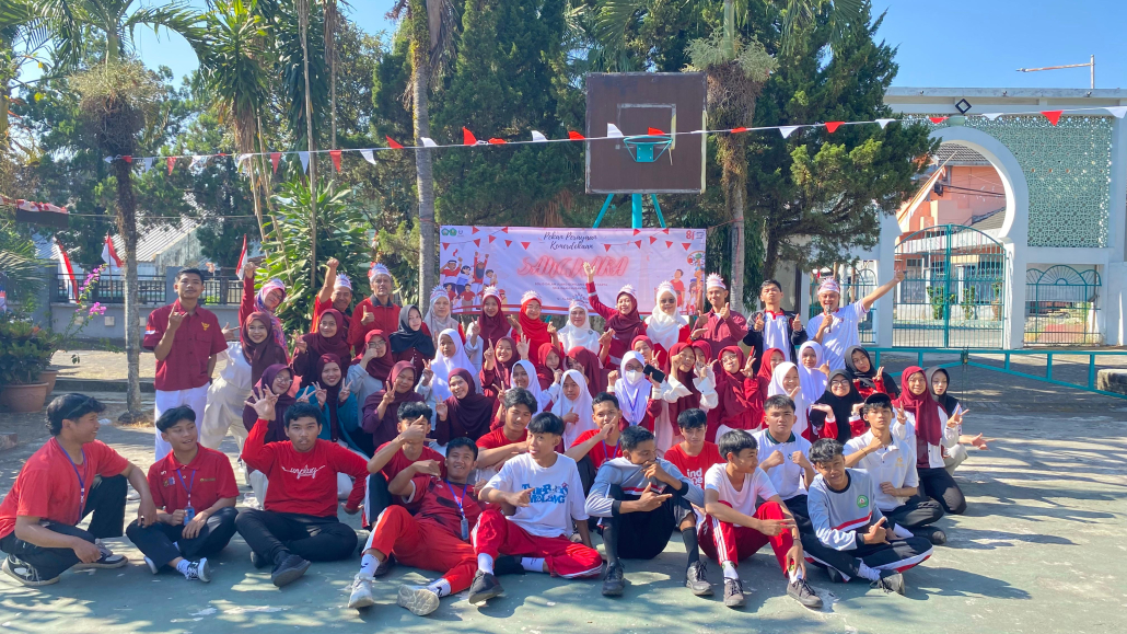 Keseruan siswa dan Mahasiswa PPLK FAI UNISMA berpose penuh semangat saat perlombaan HUT RI di lapangan sekolah.