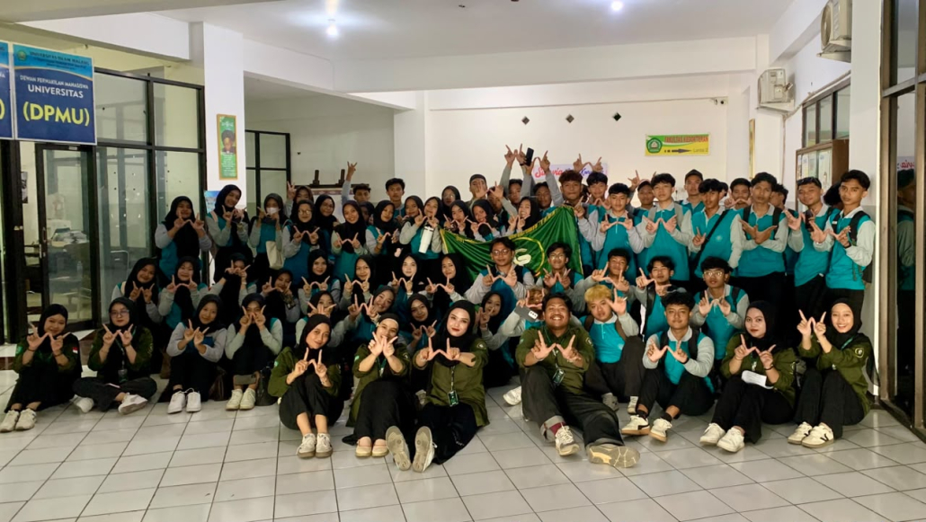 Puluhan mahasiswa baru dan pengurus UKM Kewirausahaan Golden Preneur berfoto bersama membentangkan bendera pada Master Maba UNISMA 2026 Olahraga dan Kewirausahaan.